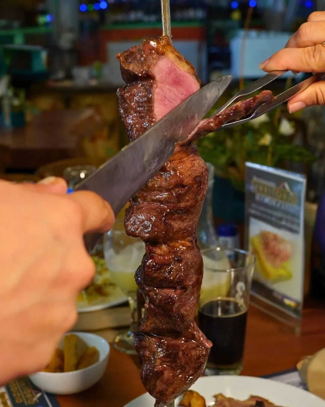 Mesero cortando carne del espetón en la mesa